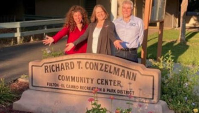Three people standing in front of the Richard T. Conzelmann Community Center.
