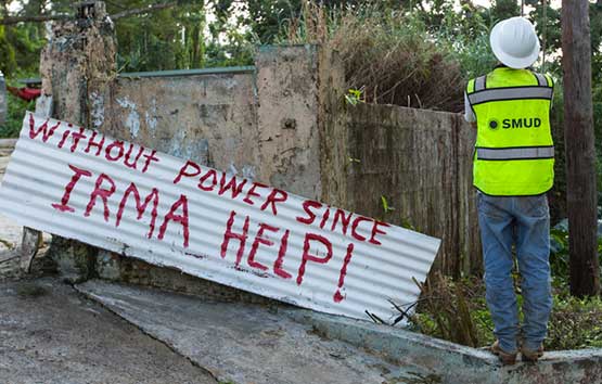 SMUD worker in front of a sign that says, 'Without power since Irma help!'