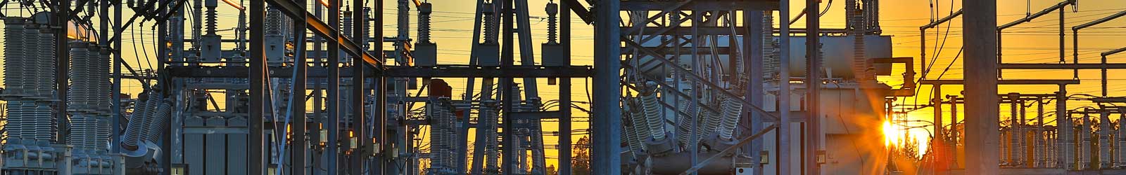 Sunset at a substation with electrical equipment in the foreground.