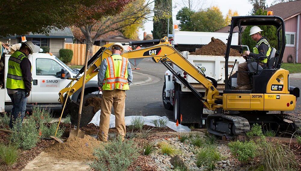 د SMUD کارګران د هستوګنې په انګړ کې د بوبکټ کیندونکي سره د اسانتیا کار کوي.