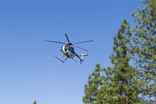 Helicopter flyer in blue sky near trees