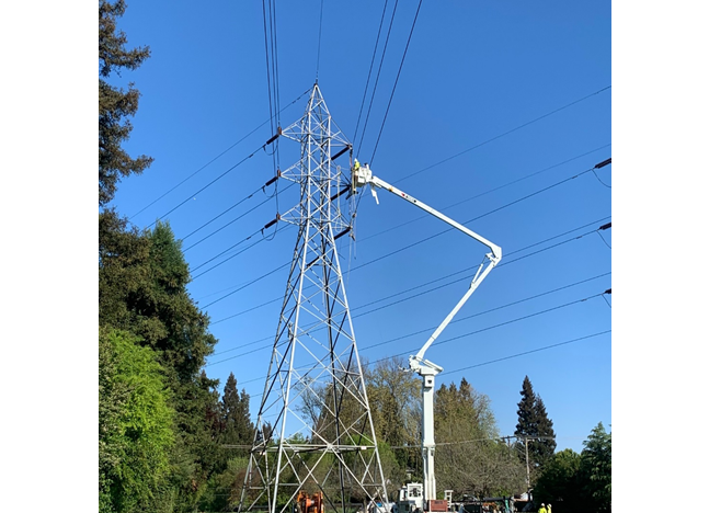 Transmission line upgrade in progress with line worker at tower