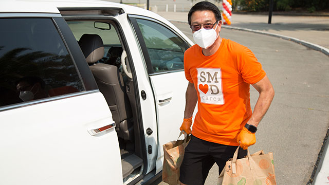 CEO Paul Lau loading groceries into a car wearing a SMUD Cares t-shirt
